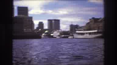 Boston USA (1975): Several Boats In A Large Bay Of Water With A City In The