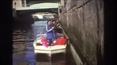 Boston USA (1975): Three People In A Boat Holding Onto Ropes Against A Wall
