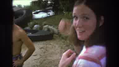 Boston USA (1975): Woman Cheers Young Child Playing In Water By A Boat While A Man