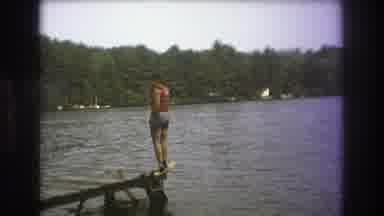 Boston USA (1975): Man Standing On Pier Near Rippling Lake And Green Trees In