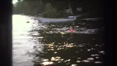 Boston USA (1975): A Man In A Life Jacket Is Floating In River Beside His Small