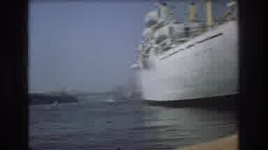 Boston USA (1975): Seated In The Water On A Small Boat Next To A Large White Ship