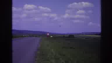 France-1967: Yellow Car Approaches on Rural Road Between Farms and Mountains