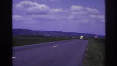 France (1967): Yellow Truck Driving Open Road By Distant Mountains