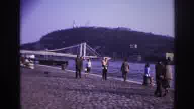 France (1967): Several People Walking A Cobblestone Area That Slopes Down To The