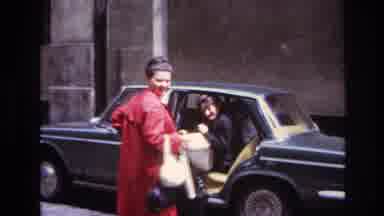 France (1967): Woman Sits In Back Seat Of Old Car And Other Woman In Red Coat