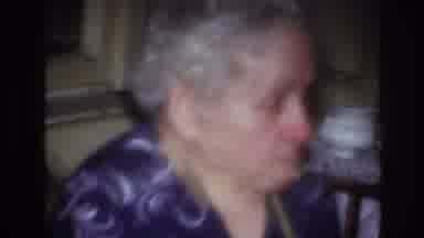 France (1967): Elderly Caucasian Woman In Purple Shirt Eating A Snack
