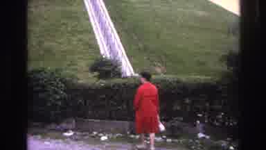 Paris France (1967): Woman Stands In Front Of Hedge In A Red Coat