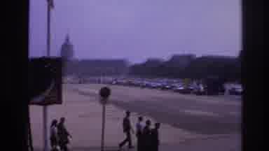 Paris France (1967): People Walk On A Sidewalk Toward A Busy Road Intersection