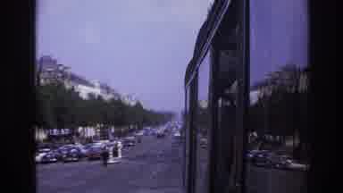 Paris France (1967): A Bus Moving Through A Town With Many Shops And Buildings