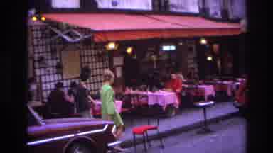 Paris France (1967): Two Women Walk By An Outdoor Cafe Where A Man Tosses Food