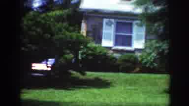 Raleigh North Carolina USA (1962): Classic Blue Car Drives Behind The Big House