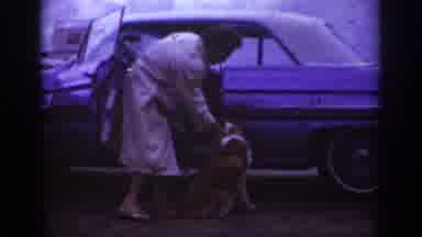 Raleigh North Carolina USA (1962): Woman Wearing A Trench Coat Attempting To Load
