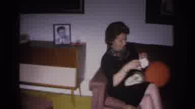 Hoboken New Jersey USA (1966): A Woman Seated On A Couch In A Living Room Opens A