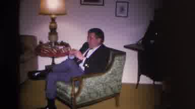 Hoboken New Jersey USA (1966): Man Sitting In Chair Lights Pipe At Evening Social