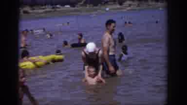 Sacramento California USA (1966): Adults Dipping Child In Lake While Another Adult
