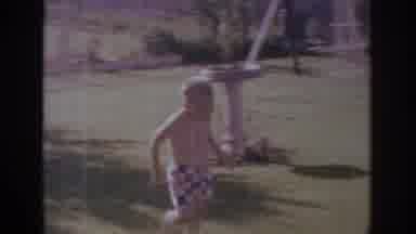 Sacramento California USA (1966): Boy Wearing Checkered Shorts Runs Through Water
