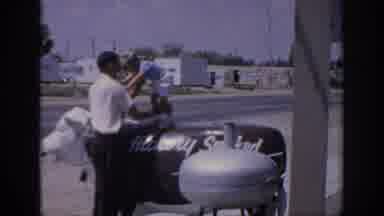 Oklahoma USA (1967): Man Helps Boy Wearing Shorts Stand On Top Animal Sign