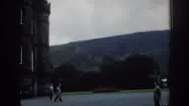 London England (1961): Two People Walking Away From Old Building Down Long Road