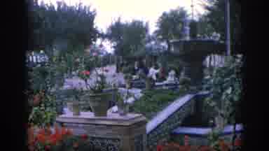 SPAIN-1966: People Visit A Beautiful Garden Full Of Flowers And A Small Castle