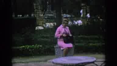 SPAIN-1966: Elegant Woman Sitting In Tree Lined Square Surrounded By Trees And