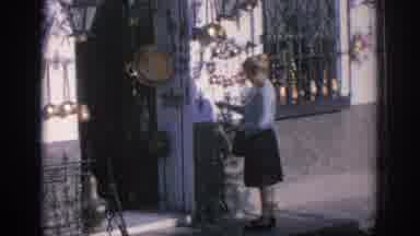 Spain (1966): A Woman Browses Decorations Outside Shop And Grey Bus Drives Around
