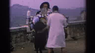 Spain (1966): A Woman Picking Out Items From A Man In A Beard Holding The Pile