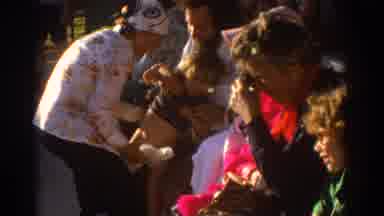 Miami Florida USA (1971): Woman Putting Diaper On Child Sitting In A Man's Lap
