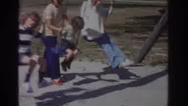Miami Florida USA (1971): Two Kids Swing On Swings As One Gets Pushed By A Woman