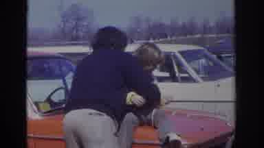 PHILADELPHIA PENNSYLVANIA USA-1973: Man Helping Child Onto Orange Classic Car