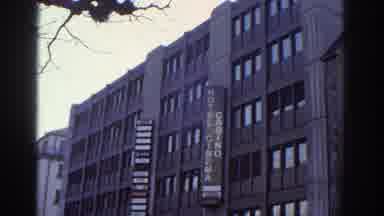 Bern Switzerland (1976): Woman Stands On Empty Sidewalk Next To Tall Hotel