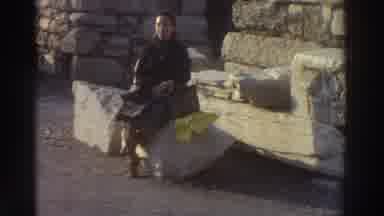 Greece USA (1976): Young Lady Distracted By Camera Person Calling While Sitting On