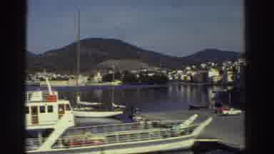 Greece (1976): A Boating Dock With Boats On Water And A Woman Standing By Tables