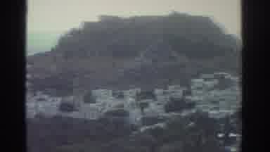 GREECE-1976: Panning Shot Of A Rocky Ocean Side Landscape Covered In Small Plant
