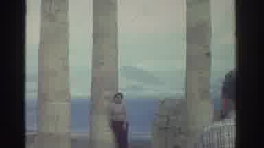 GREECE-1976: Woman Standing By Ancient Seaside Column Ruins On Windy Day