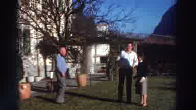 Greece (1976): Woman Sitting On House Steps Men Standing On Lawn Talking