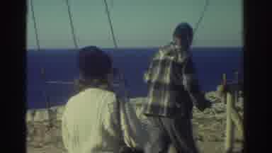 Greece (1976): Old Man Hangs Up His Fishing Rod To Smoke With Woman Walking Up