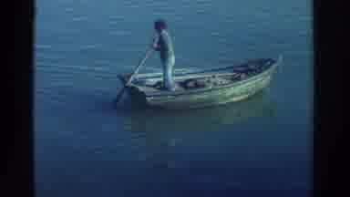 GREECE-1976: Boy Rowing Small Boat On Calm Water