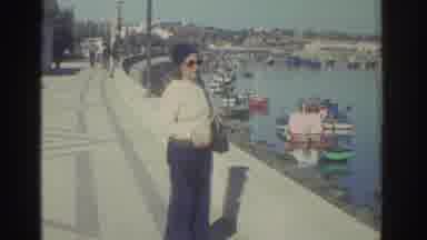 GREECE-1976: Woman on Harbor Promenade with Boats in Background