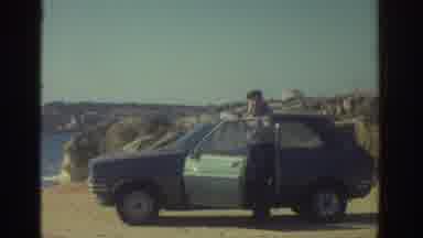 GREECE-1976: Man In Hat With Blue And White Hatchback On Coastal Cliffs
