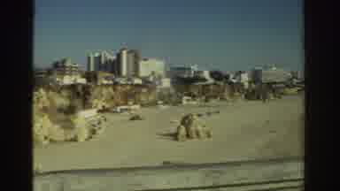 Greece (1976): Sliding Screen Of Surrounding Buildings On A Beach From A Distance