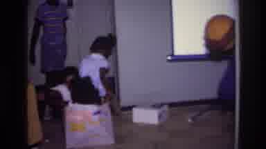 Harlem New York USA (1976): Older Child Picks Young Child Up Out Of A Play Box