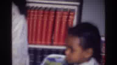 Harlem New York USA (1976): Baby Rubs Its Face In Front Of Books While Holding