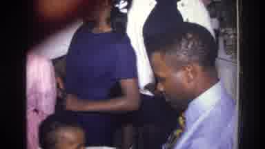 Harlem New York USA (1976): Woman Sitting At Table Man Dances With Toddler At