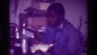 Harlem New York USA (1976): Black Man In Cluttered Room Eating Food From A Bowl