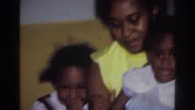 Harlem New York USA (1976): A Woman Has Two Girls On Her Lap As A Boy Gives A