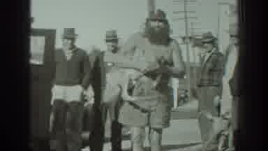 California USA (1939): Bearded Man Holding Cute Dog Surrounded By Man With Another