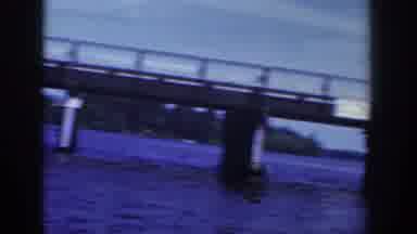 Wisconsin USA (1953): Cars Driving On A Bridge Over The Water On A Sunny Day