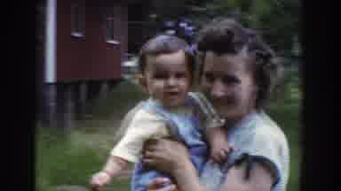 Wisconsin USA (1953): Woman Walking With Baby While Men Play On A Seesaw With