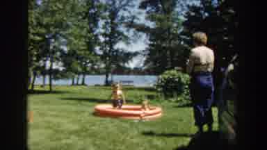 Wisconsin USA (1953): Two Children Inside A Plastic Pool And Adults Playing With